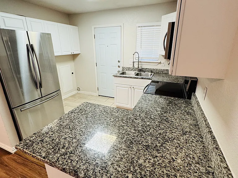 Kitchen w/granite countertops, stainless steel appliances, washer/dryer hookup, and access to the fenced in backyard.