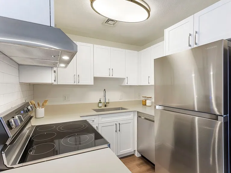 Renovated Package I kitchen with stainless steel appliances, quartz or granite countertops, white cabinetry, subway tile backsplash, and hard surface flooring