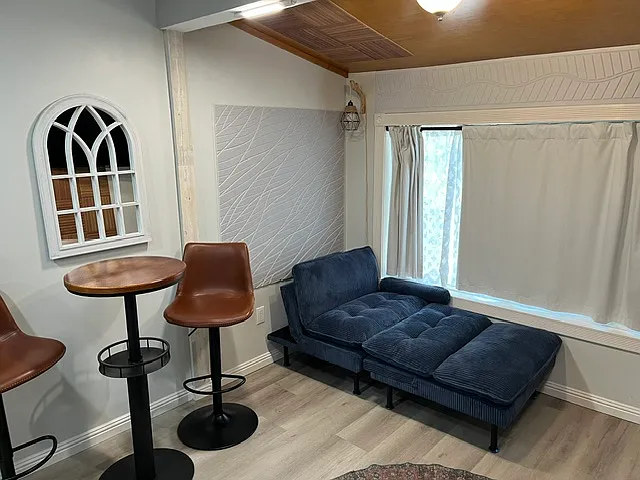 Bar stools and table. Night light in corner for reading. A new blue fold out couch lounger that also turns into a bed. Super comfortable. Black out white curtains with double liner with option for light to come through.