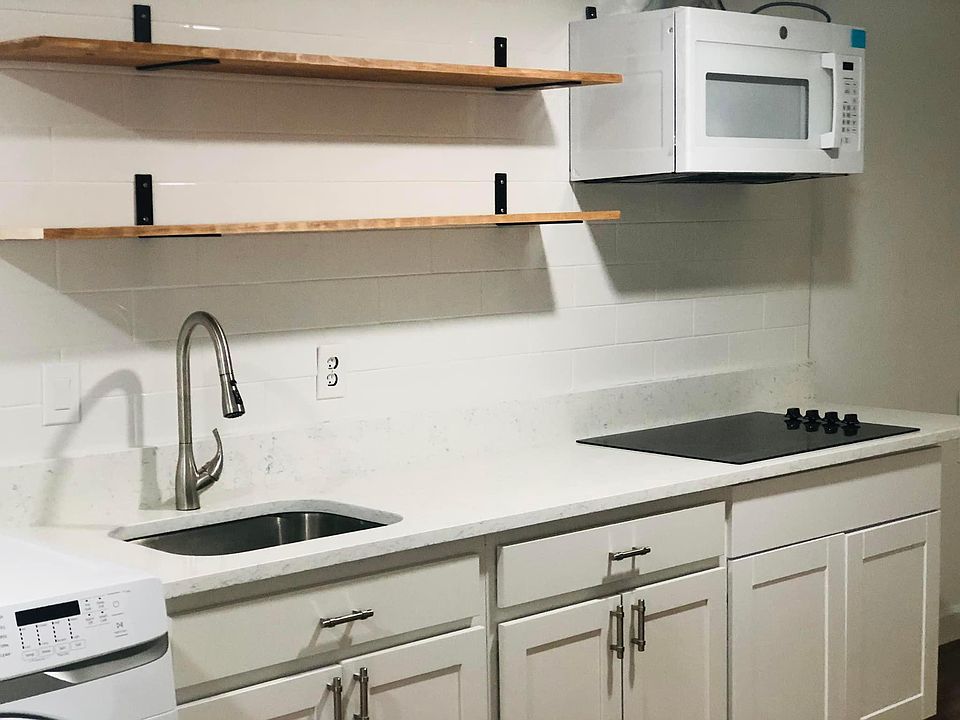 kitchen with sink, garbage disposal, stovetop, microwave with vent and shelves
