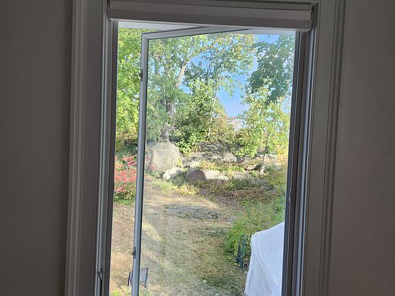 View of the backyard, looking east, as seen through a casement window.