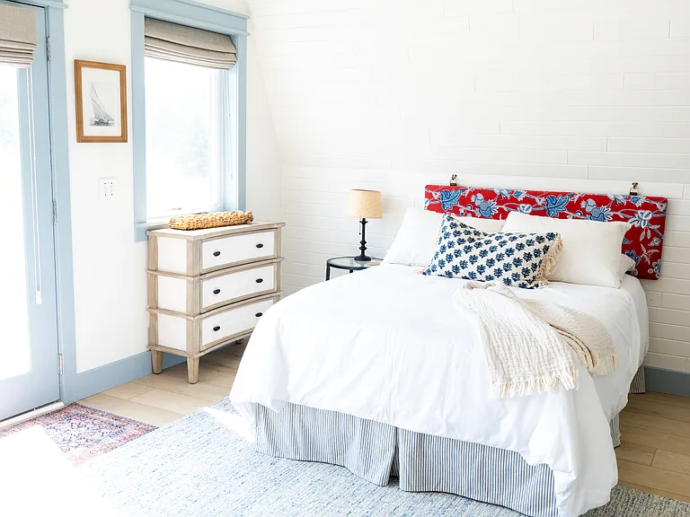 The second bedroom includes two full beds, two small dressers, a closet, a desk, and French doors that open out to the expansive back deck that overlooks vineyards.