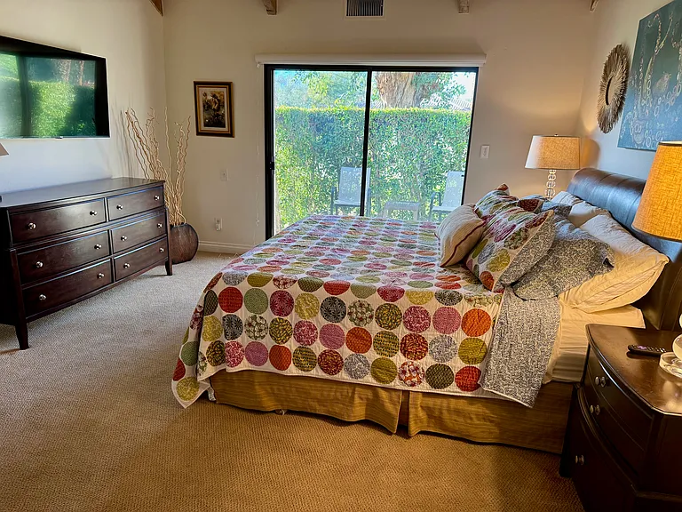 Primary bedroom looking out at private patio with new 50" smart Roku TV on left.