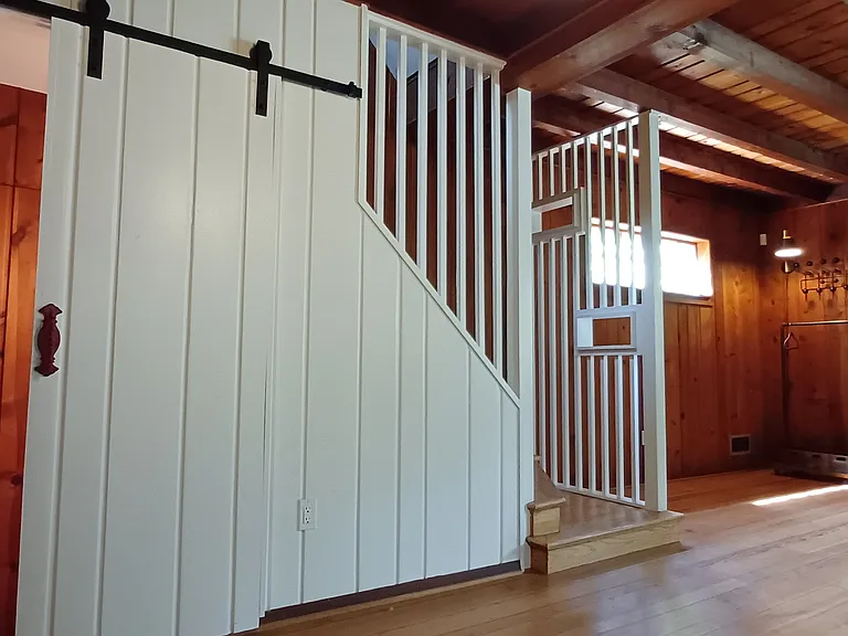 Basement stairs through white sliding farmhouse door.