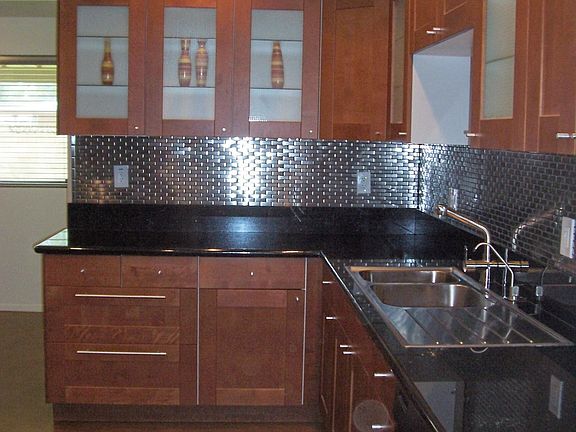 Note the back-lit glass fronts on the wood cabinets and black granite counters