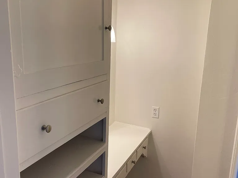 Dressing area outside bathroom has built-in cabinets and a sitting area (like a desk/makeup area)