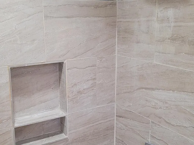 Bathtub with a rain shower head and a niche for bath/shower accessories