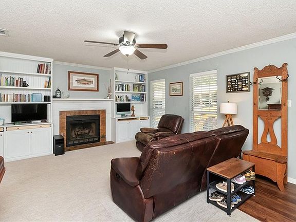 Living area with visible vents, ornamental molding, and ceiling fan