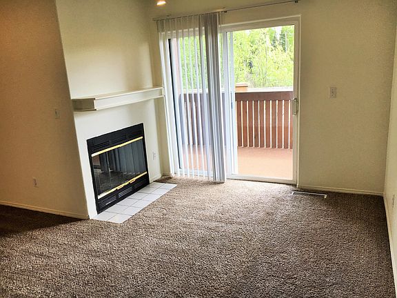 Living room w/ wood burning fireplace and spacious private patio