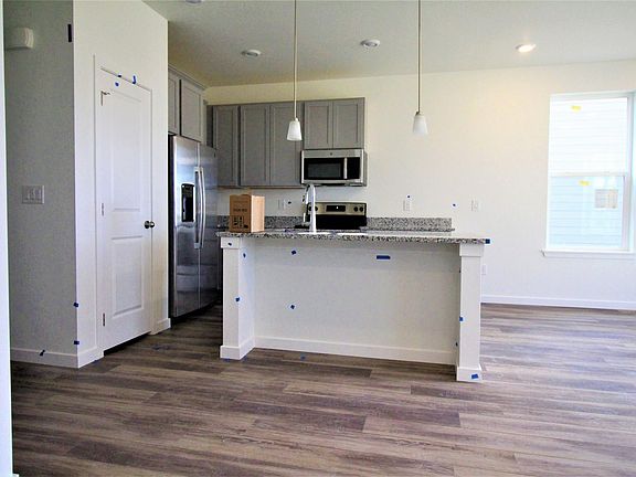 Step into the kitchen appointed with large island, stainless appliances and granite countertops. Missing cabinet to the right of the microwave - to be installed soon.