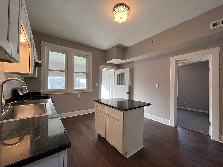 Newly renovated kitchen with granite countertops, crisp white cabinets, brand new stainless steel appliances, food pantry, and island which opens up to the den space.
