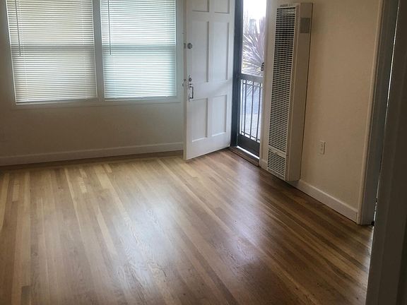 Living room with entry door. All new mini blinds and new double pained windows. New fan/light fixture. Refinished hardwood floors.