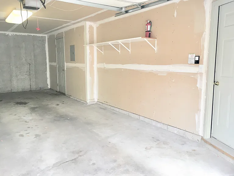 Garage, storage rack and entrance to townhome