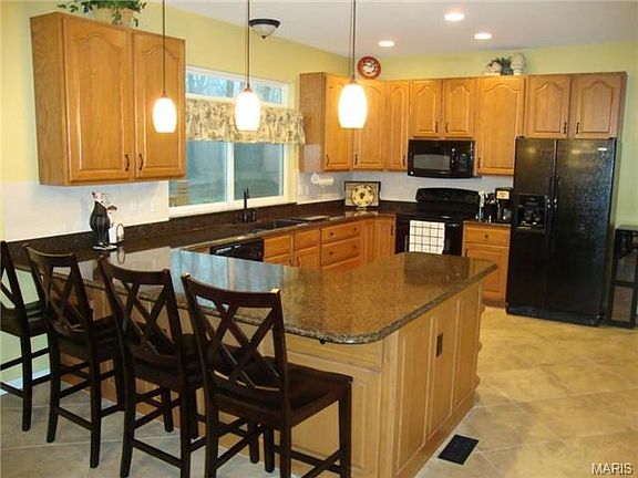 Open kitchen features granite counters, tile floor, large breakf