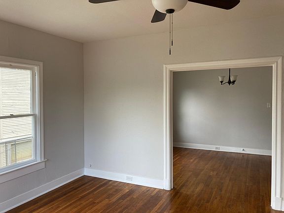 An archway connects the living room with a spacious dining room. Overhead lighting throughout is matched in bronze finish, with most rooms featuring ceiling fans, but dining room has a chandelier.