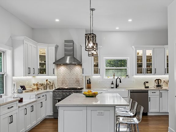 Elegantly finished with glass-front display cabinets, under-cabinet lighting, and an expansive center island complete with a breakfast bar and statement pendant lights.