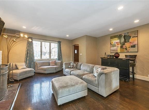 Living room boasts woodburning fireplace, recessed lighting, hardwood floors