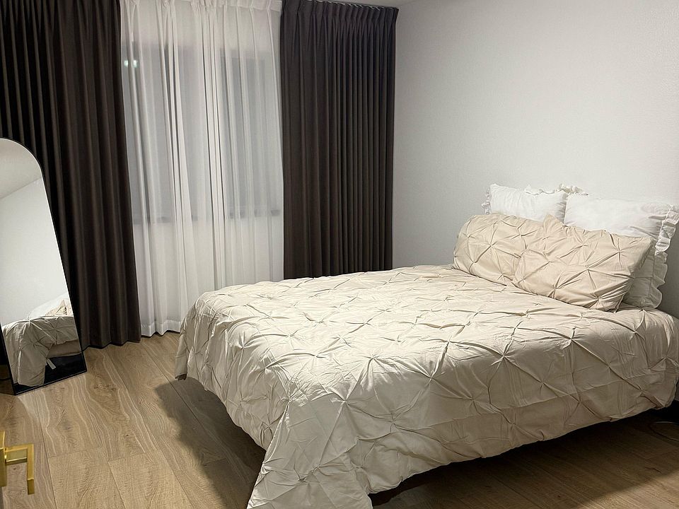 Bed in the middle of the room with a window.