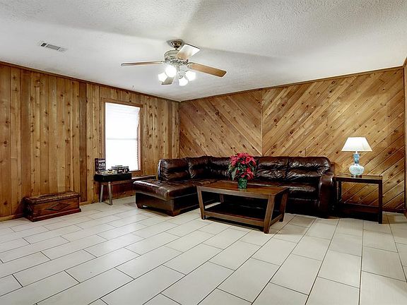 Family room features tile floors and rustic cedar wood paneling.