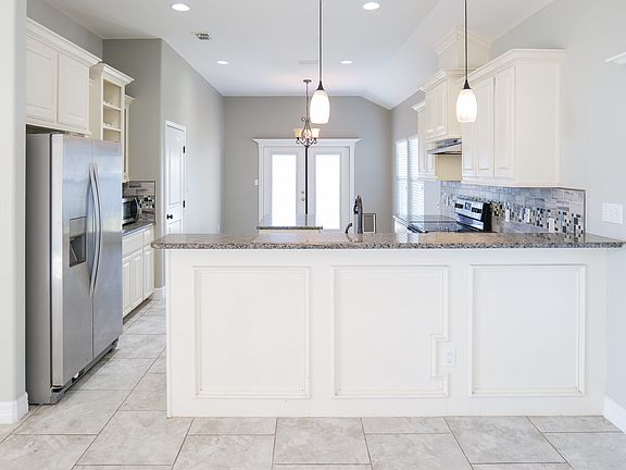 Kitchen with granite counters, fridge and stainless steel appliances. Kitchen has dining area.