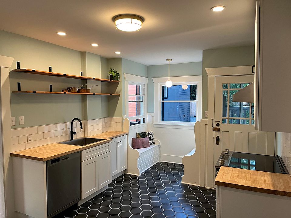 New custom kitchen featuring tile floors and backsplash, new butcher block cabinets, new appliances, original eating nook, and custom open shelving