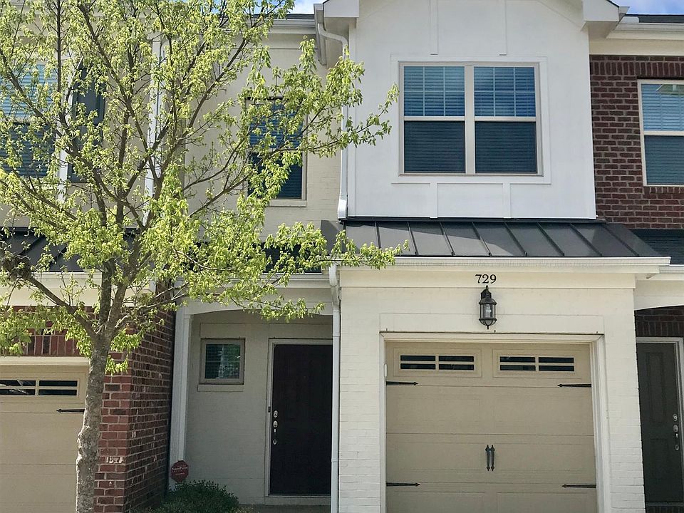 Quaint white brick front with single parking space in front of home in addition to single car garage