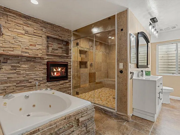 Spa-style bathroom with a jetted soaking tub, glass-enclosed walk-in shower, and long vanity with ample storage.
