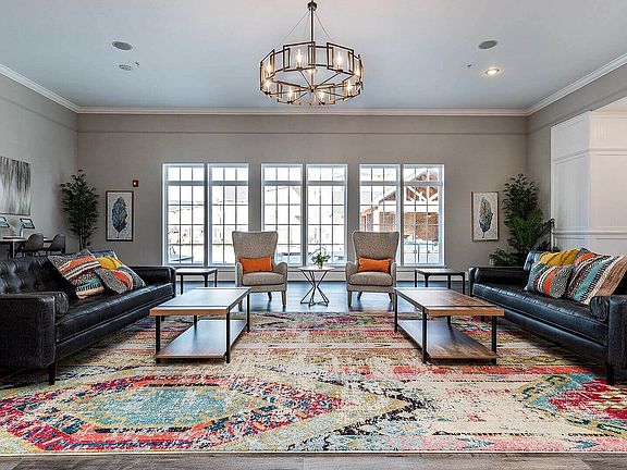 Chic and welcoming living room with large windows, modern lighting, and vibrant decor, offering a perfect blend of comfort and elegance.