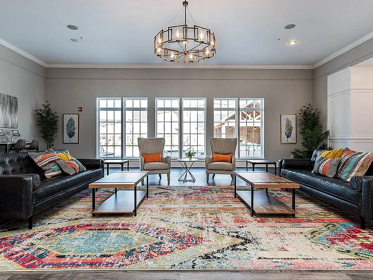 Chic and welcoming living room with large windows, modern lighting, and vibrant decor, offering a perfect blend of comfort and elegance.