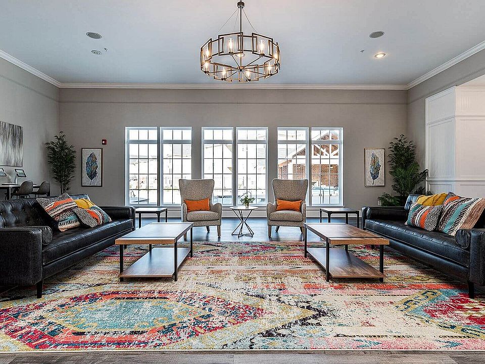 Chic and welcoming living room with large windows, modern lighting, and vibrant decor, offering a perfect blend of comfort and elegance.