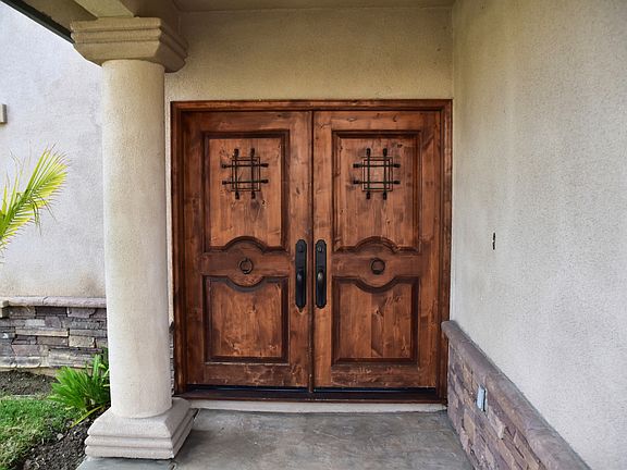 The custom, old-world front door is crafted from wood and is sheltered by a covered front porch.