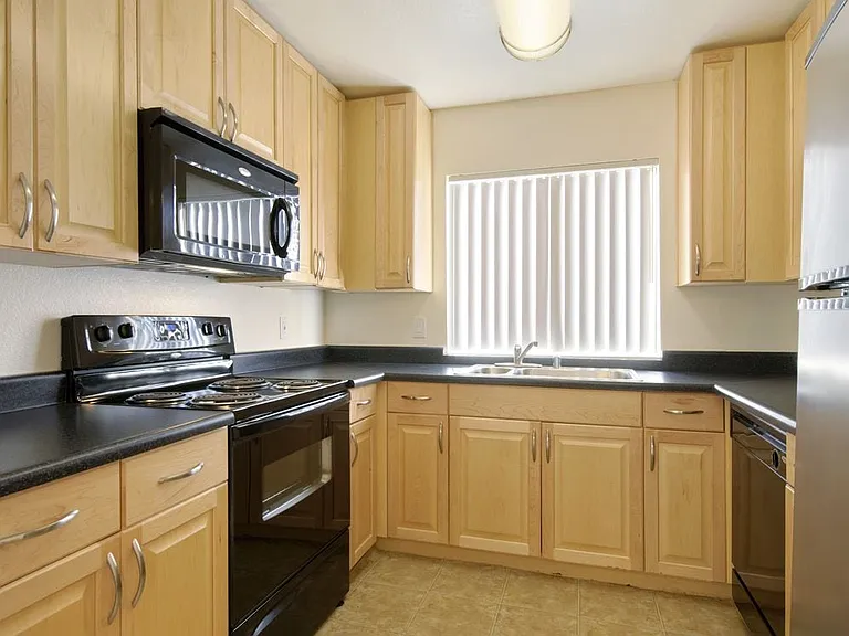 Kitchens with black appliances, black laminate countertops, and maple cabinetry