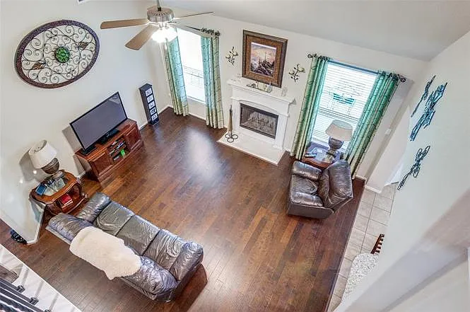 Spacious living room with hardwood floors, a fireplace, and seating area, plus large windows for natural light.