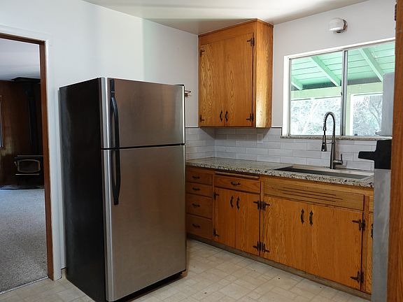 Well-maintained 1970s kitchen with generous storage, clean finishes, and a window overlooking the surrounding trees for natural light.
