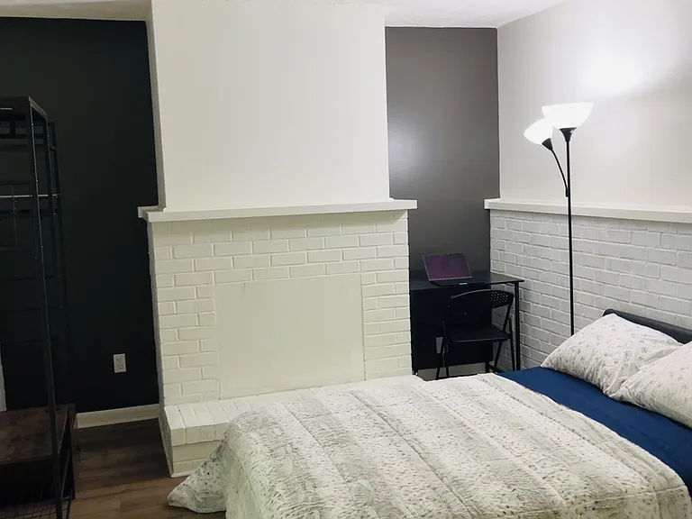 Bedroom with a full bed setup, painted brick accent walls, and space for a small desk or reading corner.