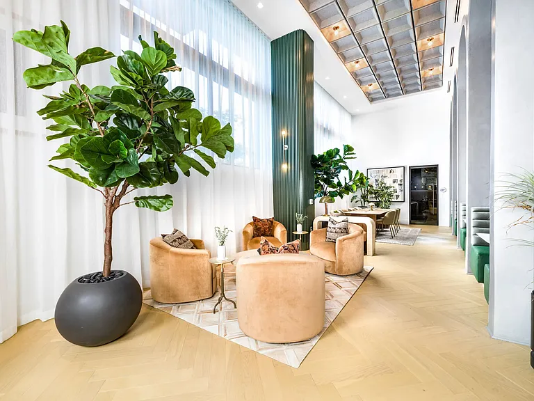Resident seating area with sculptural chairs, tall ceilings, and natural light creating an inviting setting for coworking and quiet moments.