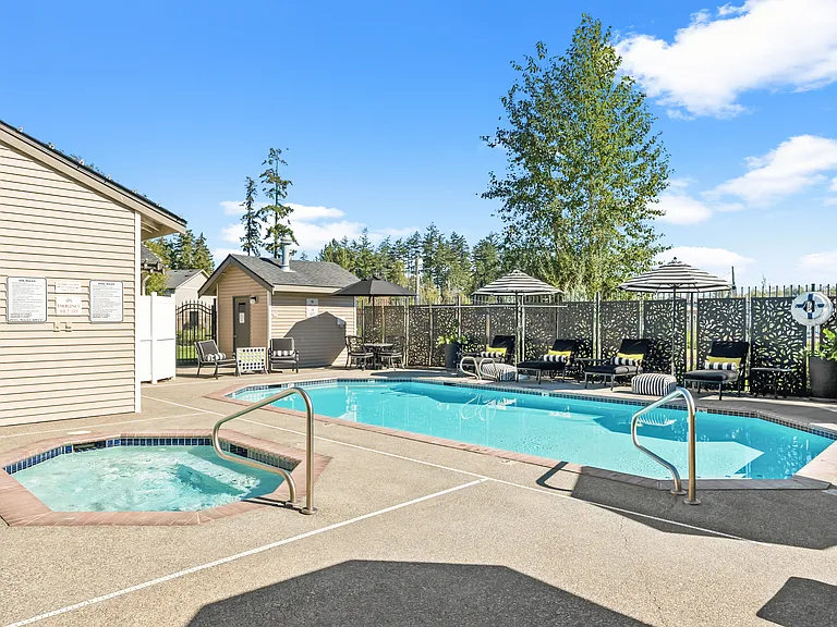 Outdoor swimming pool and spa area with seating and landscaped surroundings.