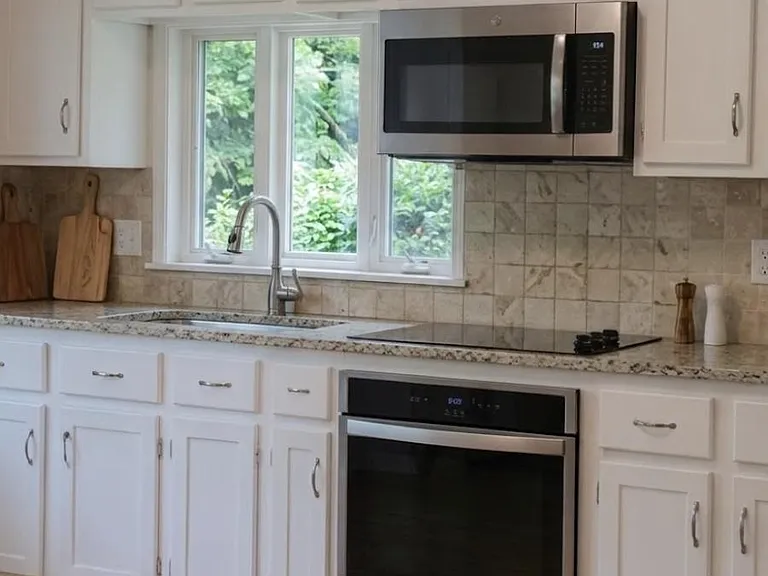 Spacious kitchen with abundant cabinet storage, tile backsplash, stainless wall oven and microwave, plus a windowed sink.