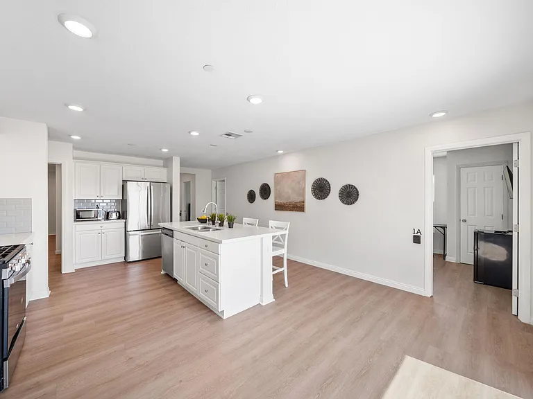 Open kitchen features a large island with seating, ample white cabinetry, and stainless-steel appliances for easy meal prep.