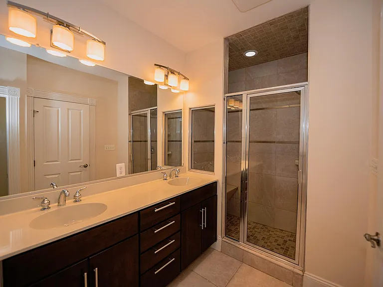Master bathroom with glass-enclosed shower with bench and double vanity