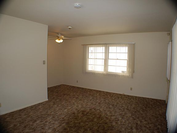 Living room taken from the corner of the room with the window air conditioning unit.(Brand New AC Unit) Double windows are along the side walkway that leads back to the garage.