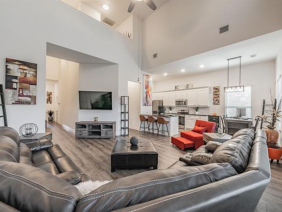 Living area with wood finished floors, a towering ceiling, ceiling fan, and recessed lighting