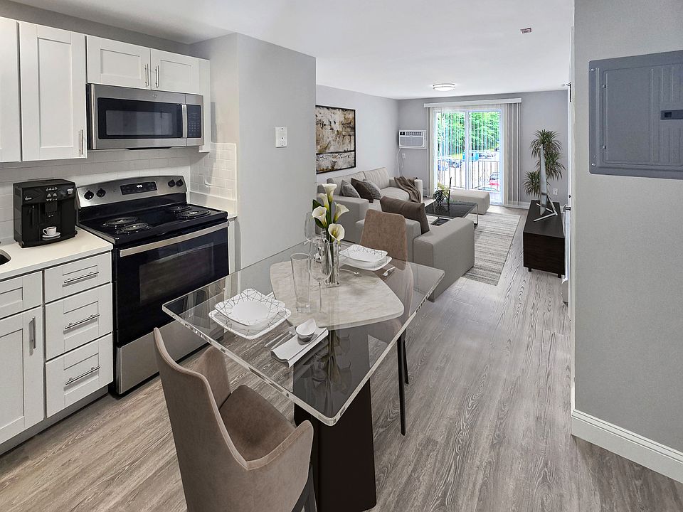 Contemporary open-plan kitchen and living room featuring sleek appliances, elegant dining area, and bright natural light through large sliding doors.
