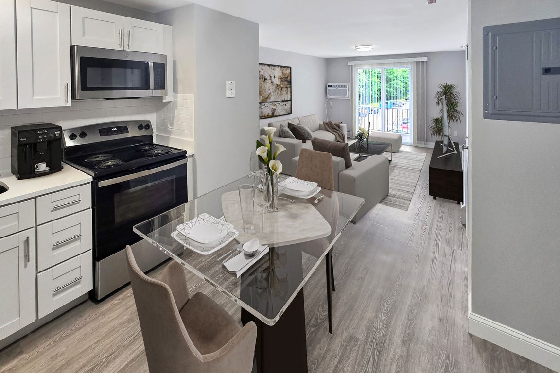 Contemporary open-plan kitchen and living room featuring sleek appliances, elegant dining area, and bright natural light through large sliding doors.