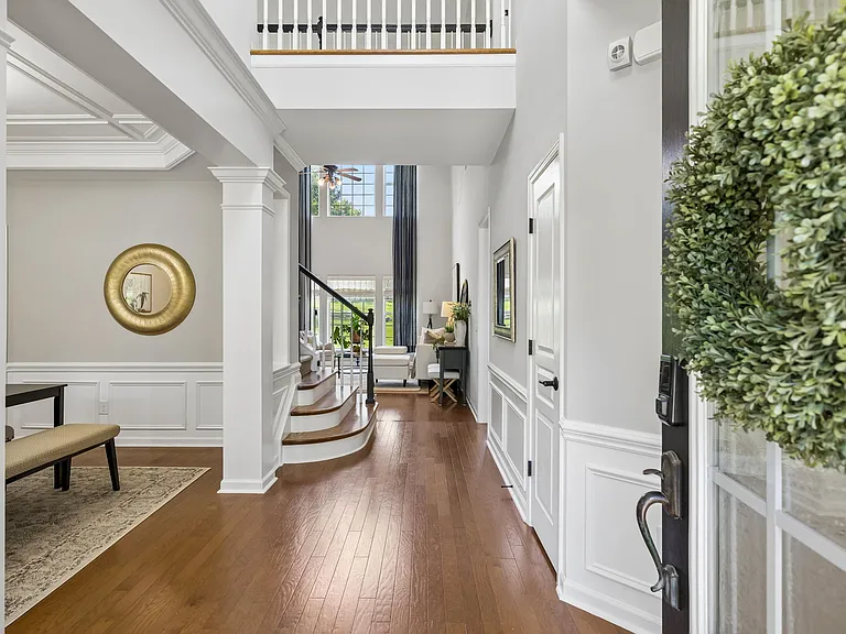 The dramatic 2-story foyer sets the tone for the home with soaring ceilings~custom millwork~elegant architectural columns! *Those wanting 1 level living- primary ensuite/laundry/office/dining/kitchen/living room/garage access on main!