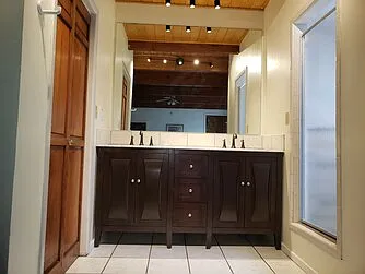 New marble top, double sink vanity in master suite downstairs, door to shower on the right, door to toilet room on left.
