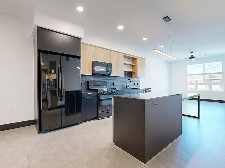 Apartment Kitchen with Stainless Steel Appliances, Dining and Living Room with Wood-Style Flooring.