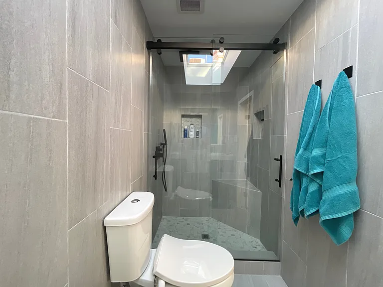 Spacious glass-enclosed rain shower with contemporary tile and premium fixtures.