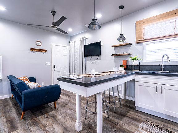 Another view of the kitchen, including the entrance, mounted TV, functional shelving, keyless entry, heavy curtains in living area and kitchen sink. Double sided.