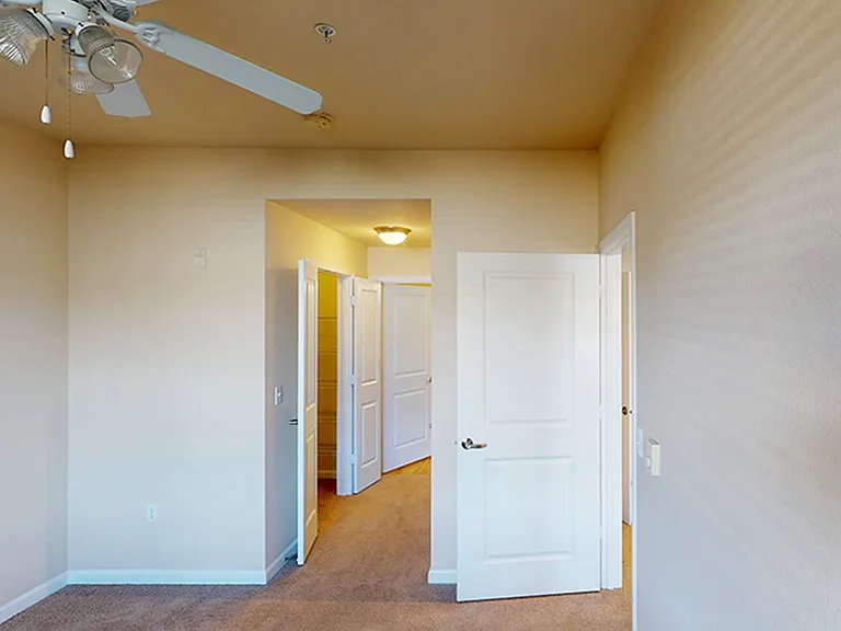 Spacious apartment bedroom with plush carpet flooring.
